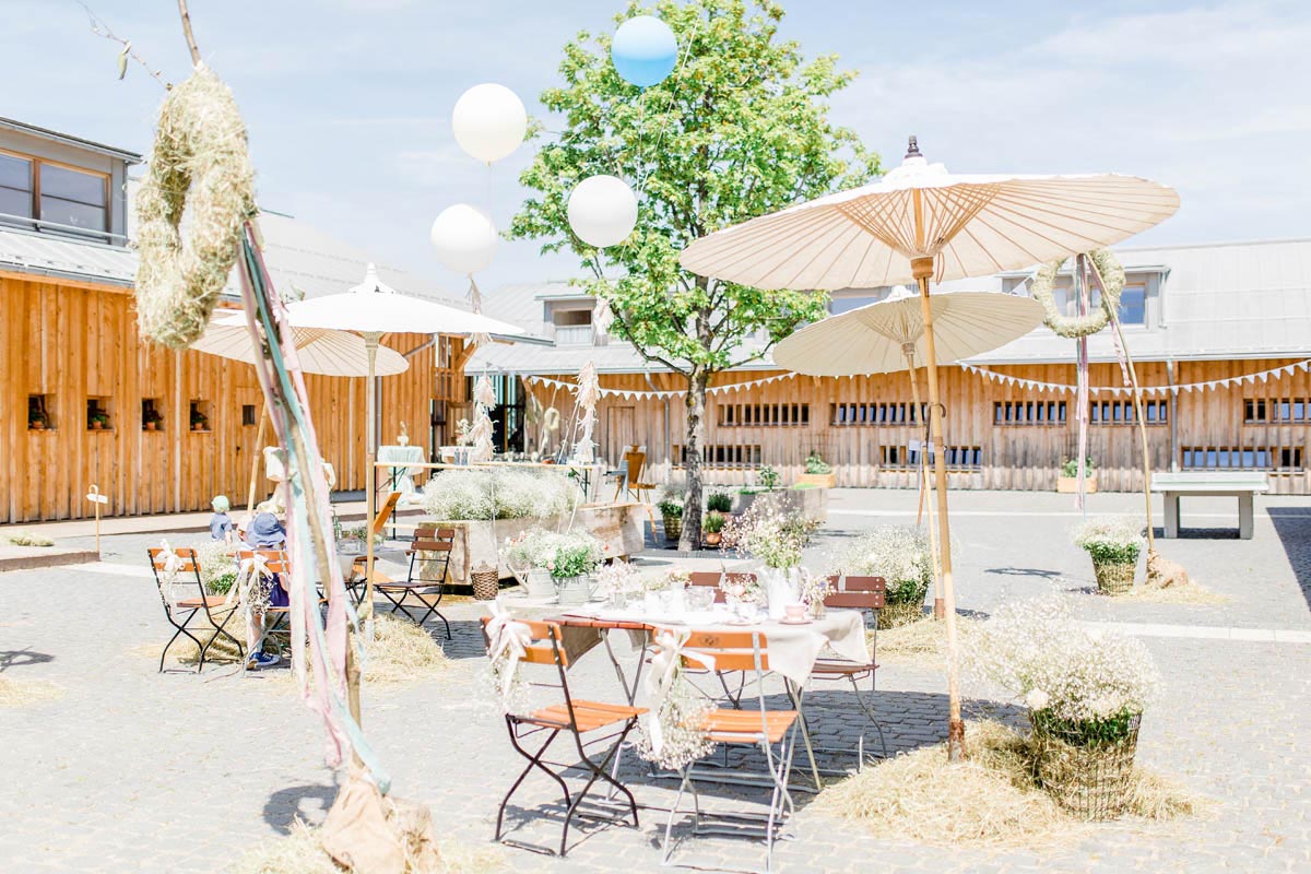 Terrasse der Alm mit Sonnenschirmen und Lampions für die Hochzeit