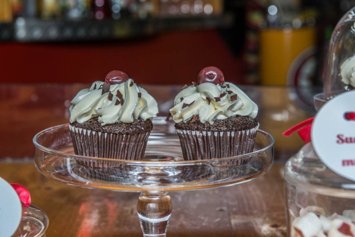 Cupcakes mit weißem Topping und Bonbons in Gläsern