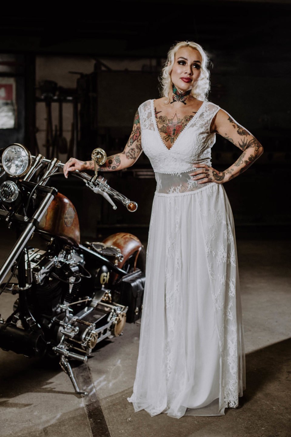 Tattoo Braut im bauchfreien Brautkleid neben Motorrad