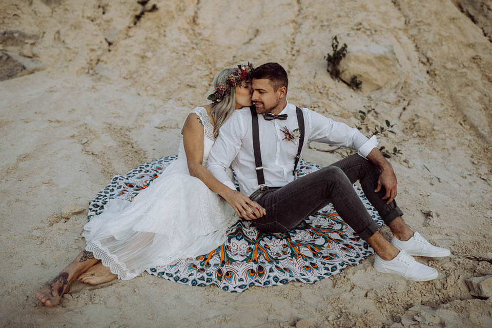 Elopement Hochzeit - Brautpaar küsst sich auf der Decke im Sand