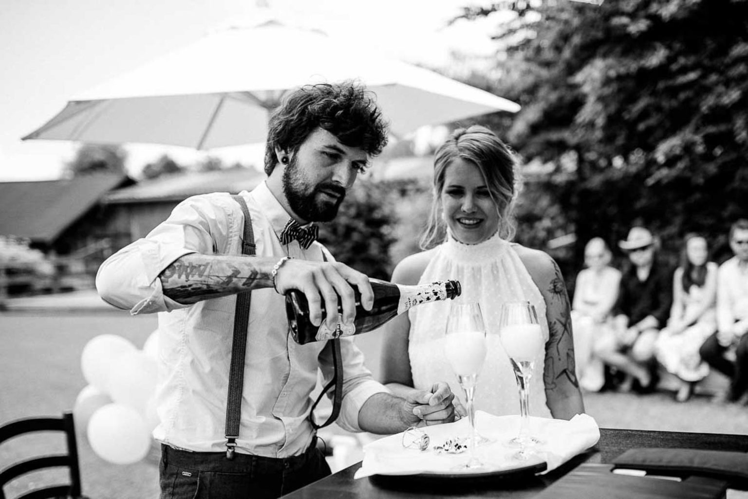 Schwarz-Weiß-Foto: Bräutigam schenkt Sekt ein, die Braut lacht