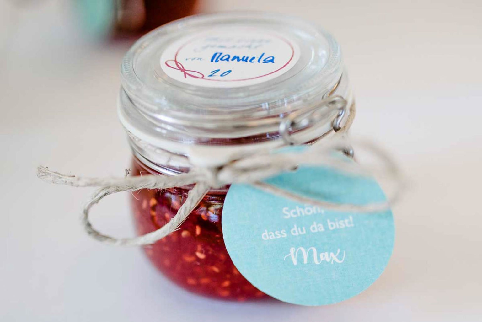 Marmeladenglas mit Himbeermarmelade und Anhänger als Gastgeschenk