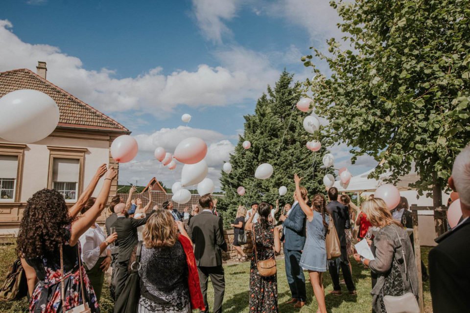 Hochzeitsgesellschaft lässt Luftballons nach der kirchlichen Hochzeit steigen