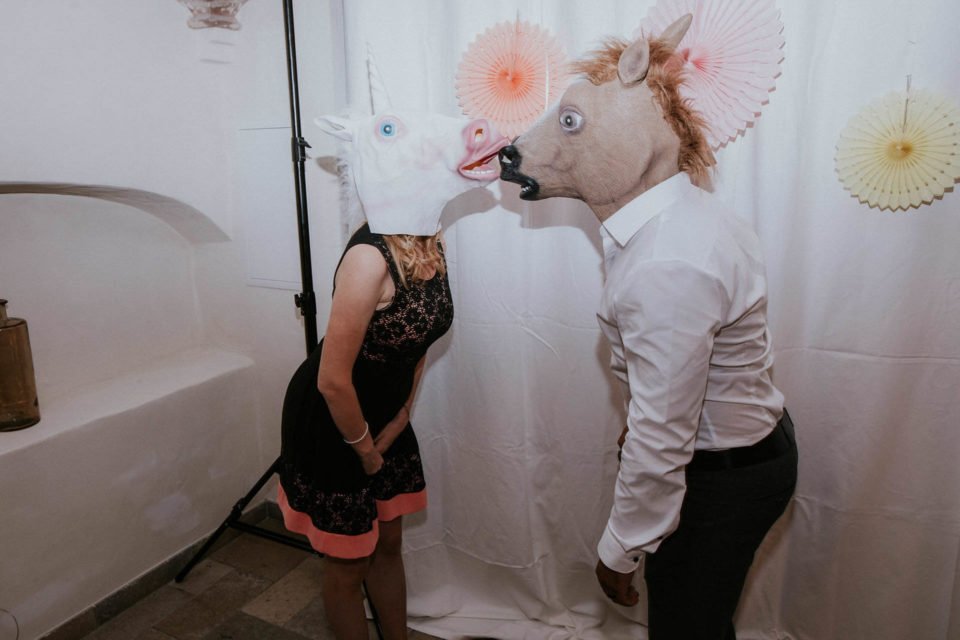 Hochzeitsgäste mit Pferdemasken, die sich küssen