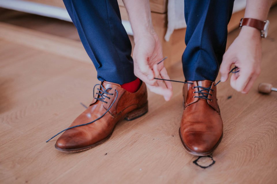 Bräutigam mit roten Socken bindet sich die Schuhe
