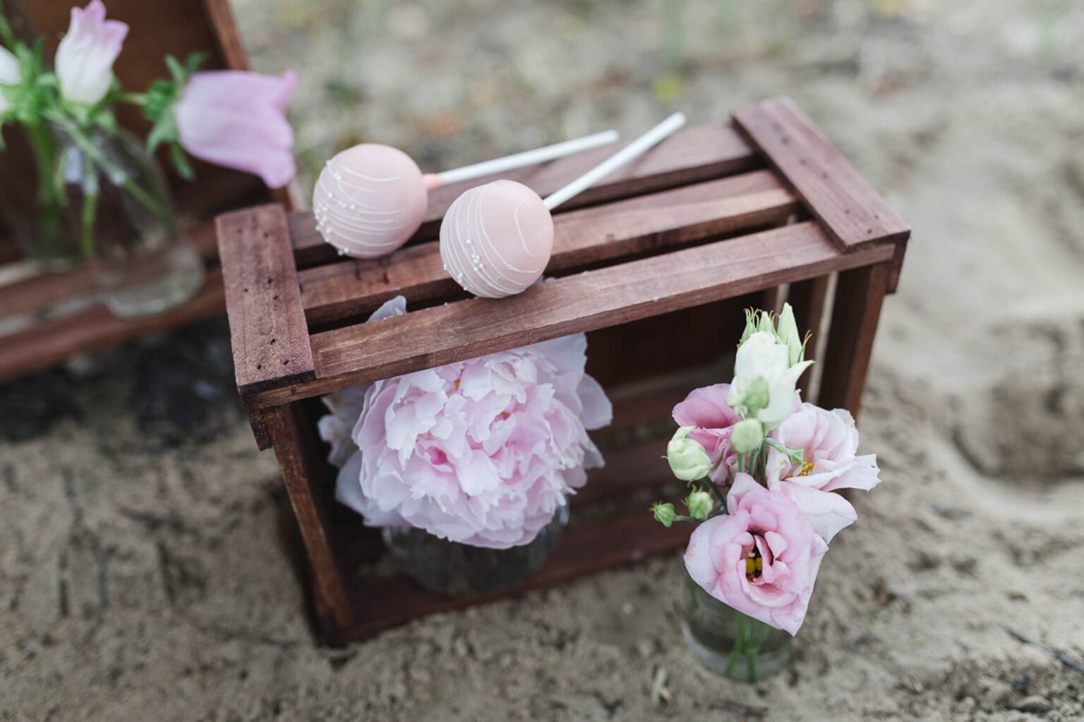 Holzkiste mit Pfingstrosen und rosa Cakepops