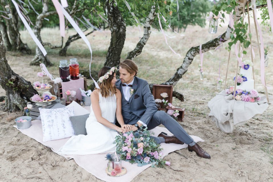Brautpaar auf Decke nach der Trauung unter Bäumen