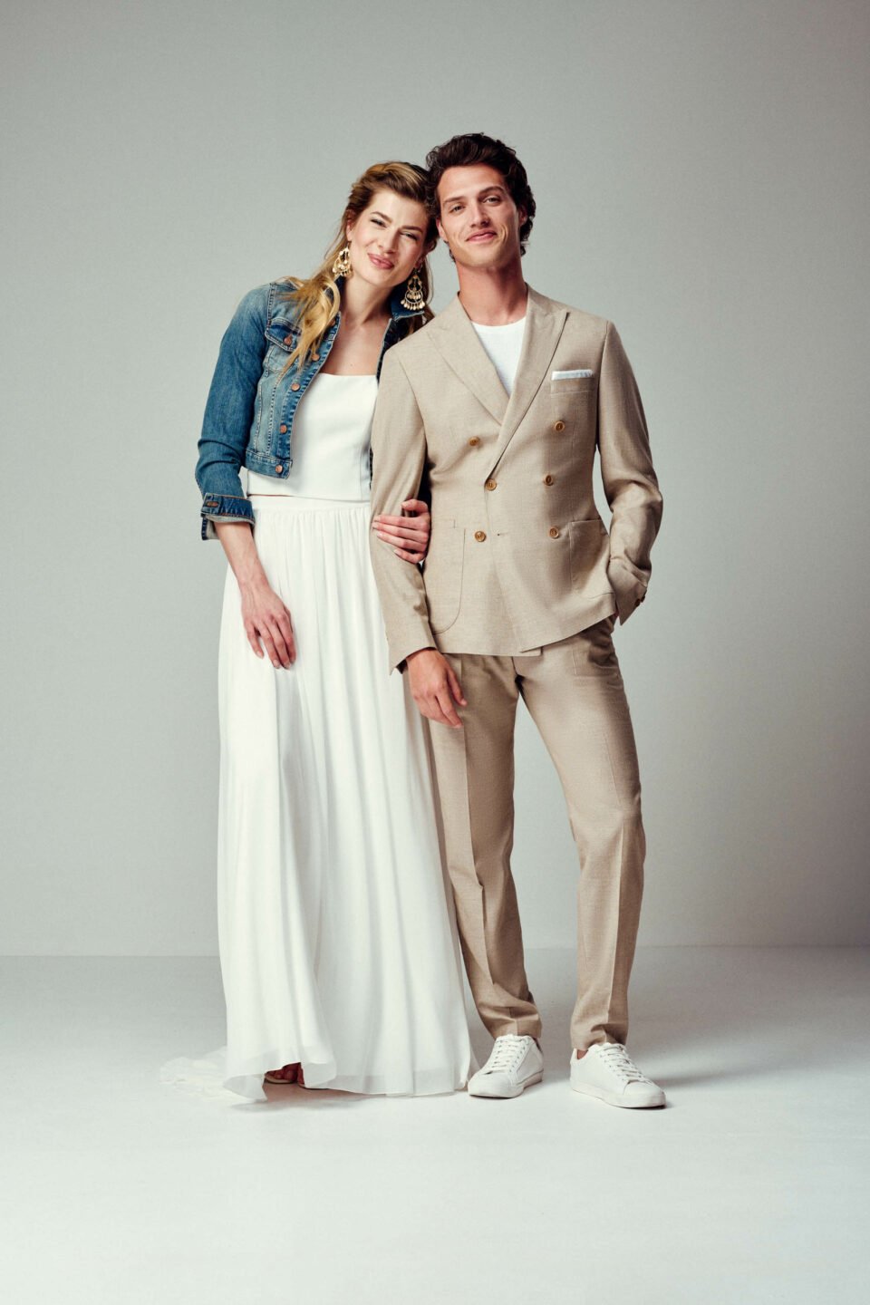 Cooles Brautpaar: Braut mit Jeansjacke im Zweiteiler, Bräutigam im lässigen, sandfarbenen Anzug