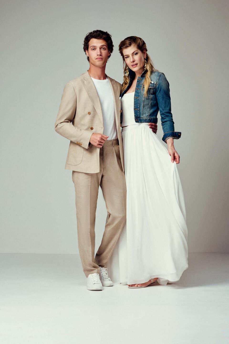 Braut im Zweiteiler mit Jeansjacke mit Bräutigam in sandfarbenen Anzug