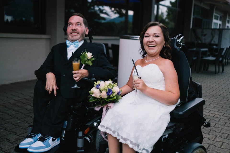 Glücklich strahlendes Brautpaar im Rollstuhl