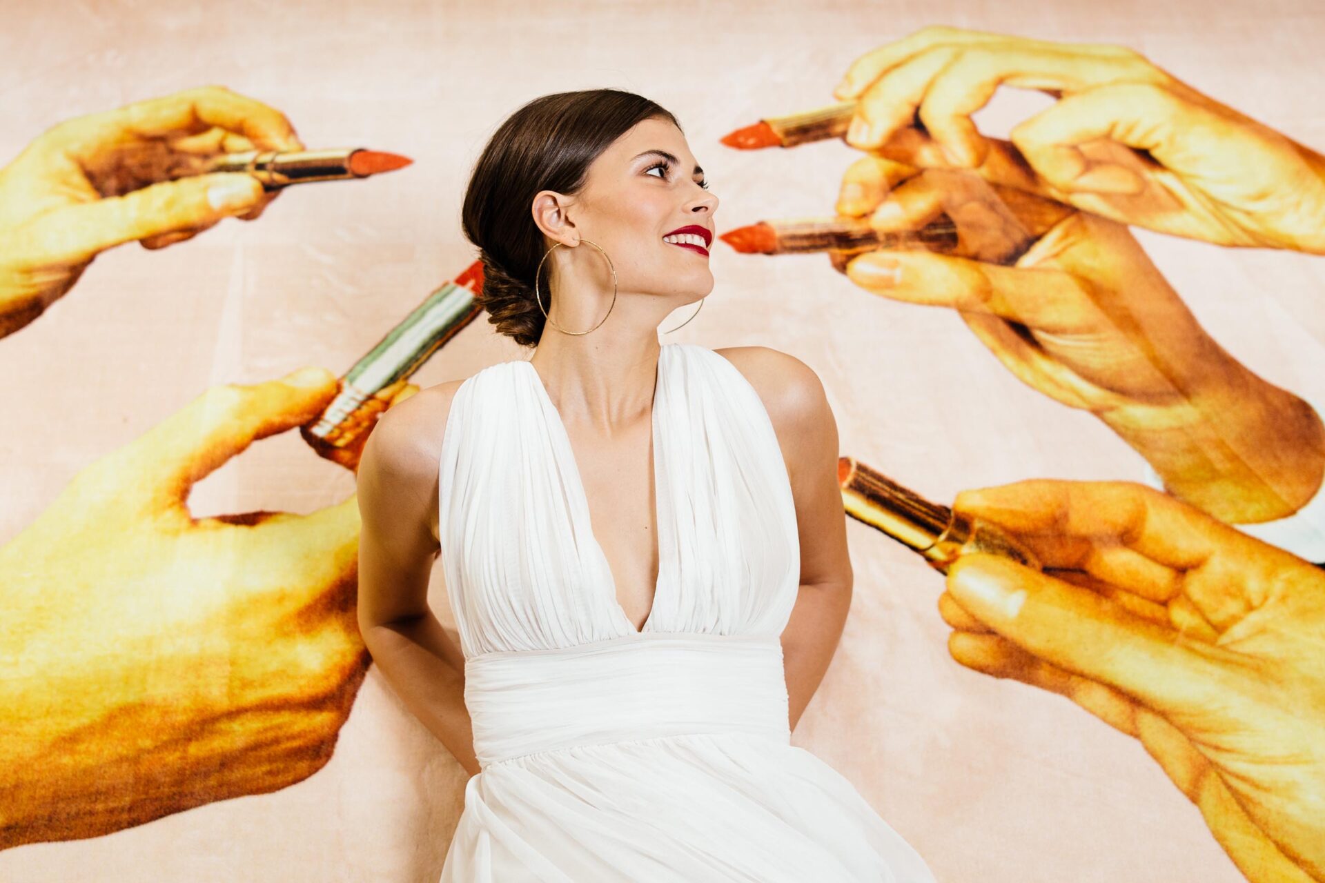 Braut liegt im Brautkleid mit Trägern auf Teppich mit rotem Lippenstift