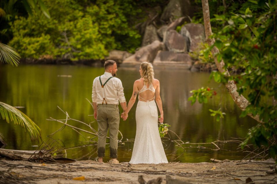 Brautpaar von hinten Hand in Hand bei Destination Wedding auf den Seychellen