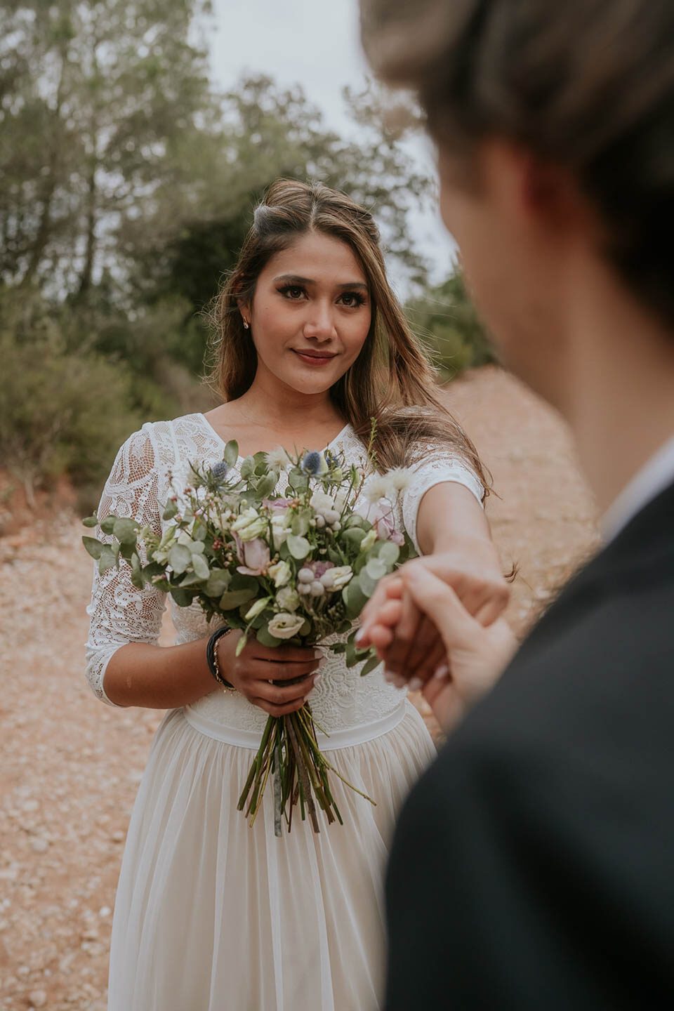 Braut mit Brautstrauss streckt Hand zum Brautigam aus