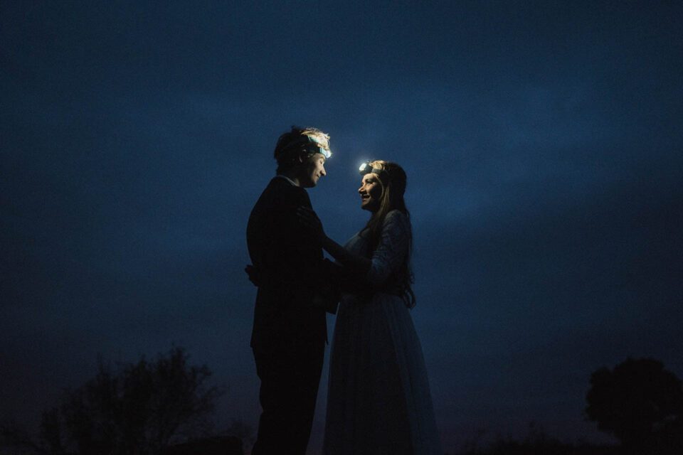 Brautpaar mit Stirnlampe schaut sich im Dunkeln an 