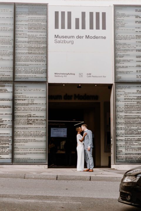 Brautpaar küsst sich in Salzburg vor dem Museum der Moderne