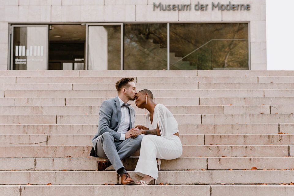 Bräutigam küsst Braut auf den Treppen des Museums der Moderne in Salzburg