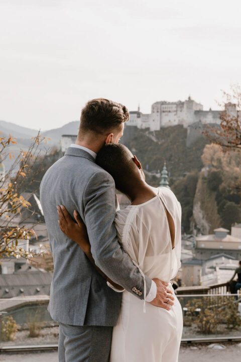 Brautpaar von hinten Arm in Arm mit Blick auf Burg in Salzburg