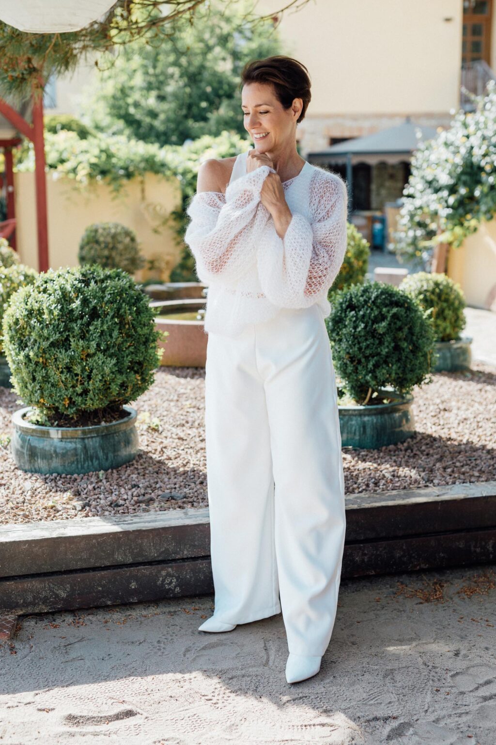 Braut in weiter Hochzeitshose P-0010 mit transparentem Strickpulli im Garten