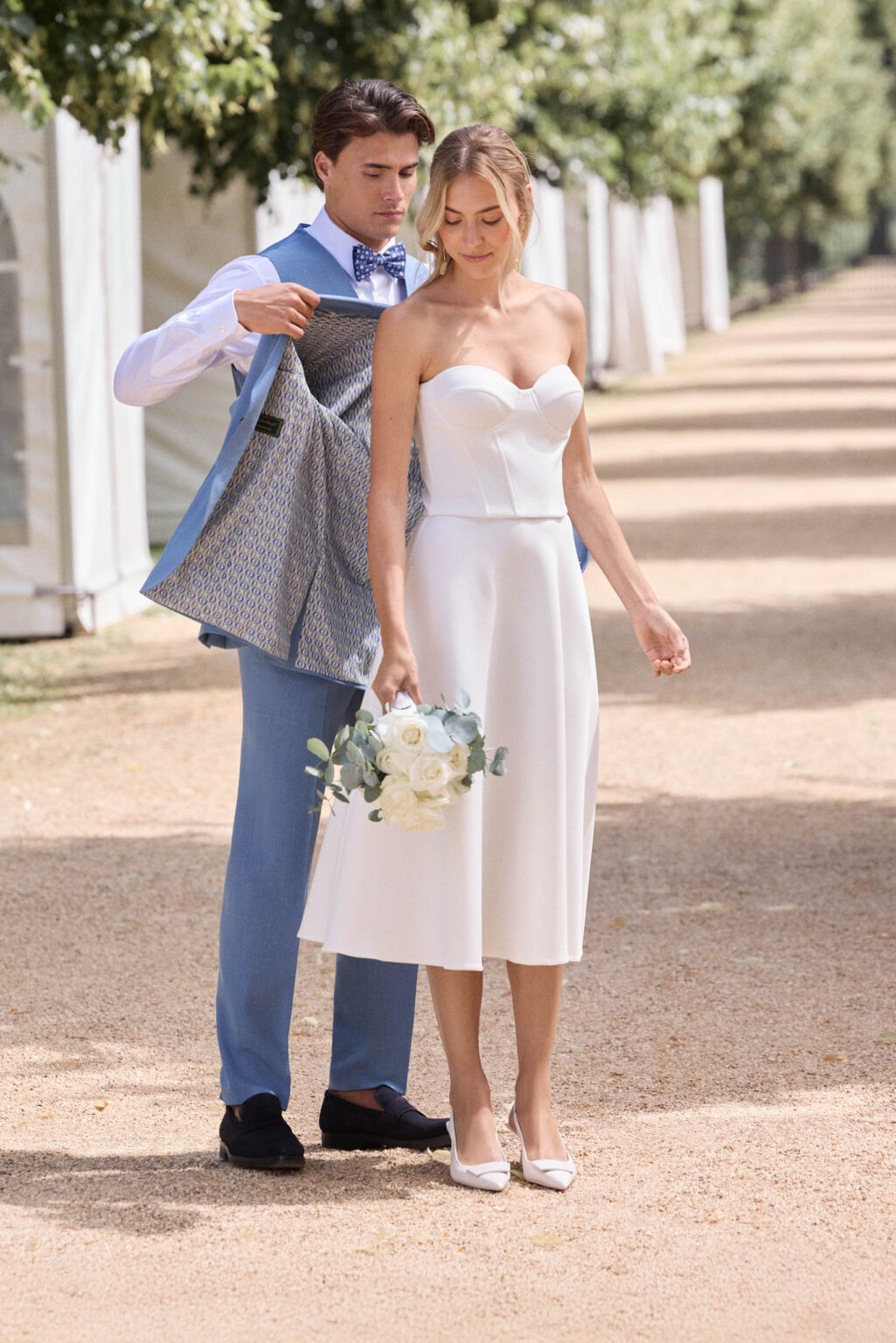Braut im kurzen Zweiteiler mit Corsage, der Bräutigam zieht sein blaues Sakko aus