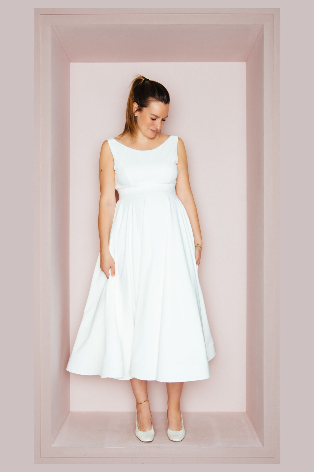 Schwangere Braut in einem wadenlangen ärmellosen Brautkleid mit rundem Ausschnitt und weitem Rock
