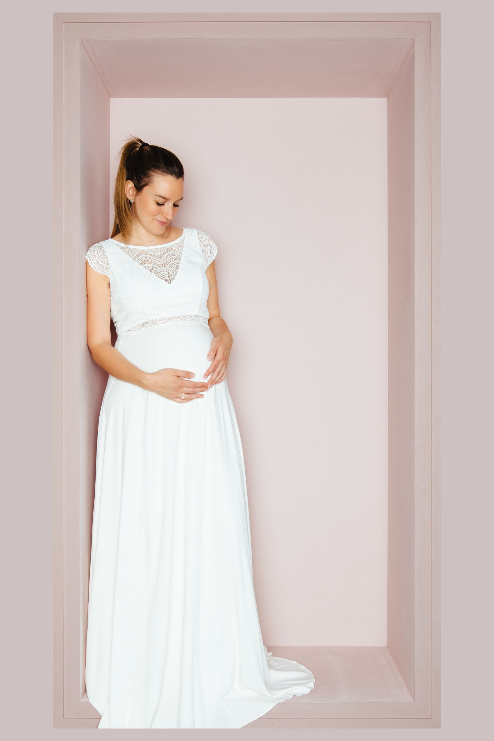 Schwangere Braut in weißem Brautkleid mit Spitzenärmeln im Wellenmuster und Empire-Linie von KUESSdieBRAUT