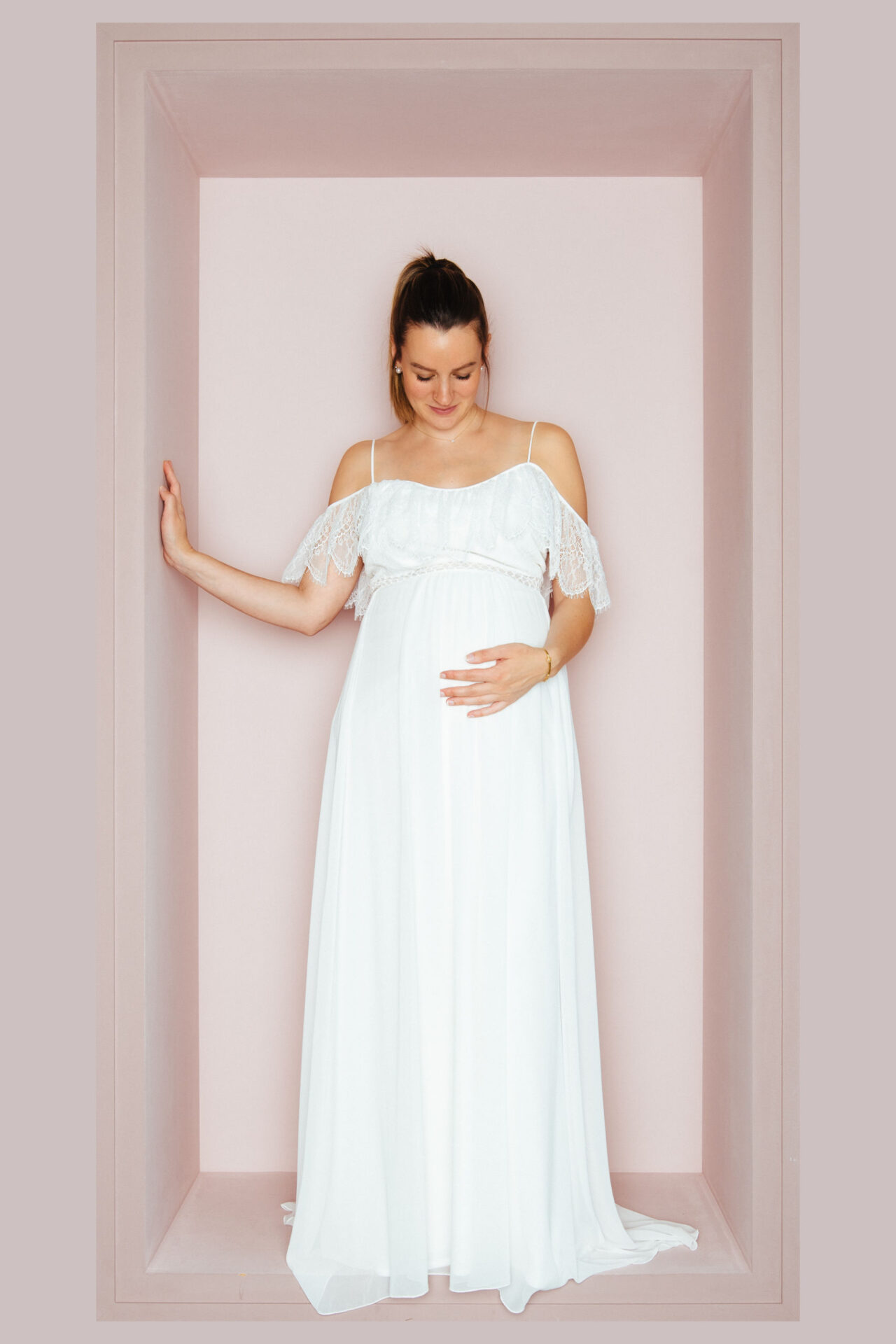 Schwangere Braut im Brautkleid mit Spaghettiträgern und schulterfreiem Spitzenvolant