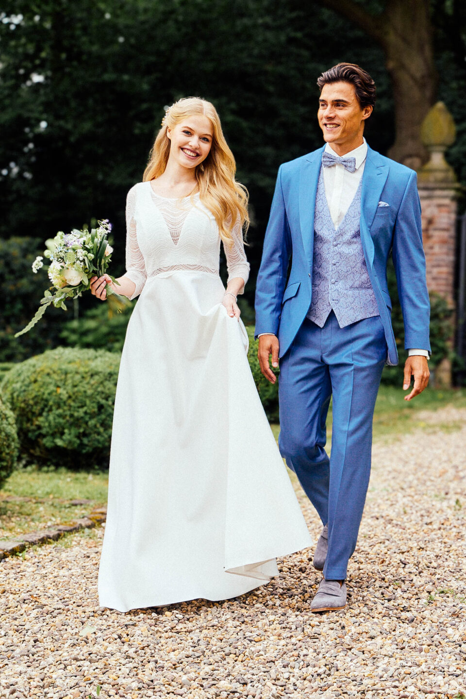 Brautkleid Bobigny mit 3/4-Arm-Oberteil aus Wellenspitze, Brautpaar im Schlossgarten