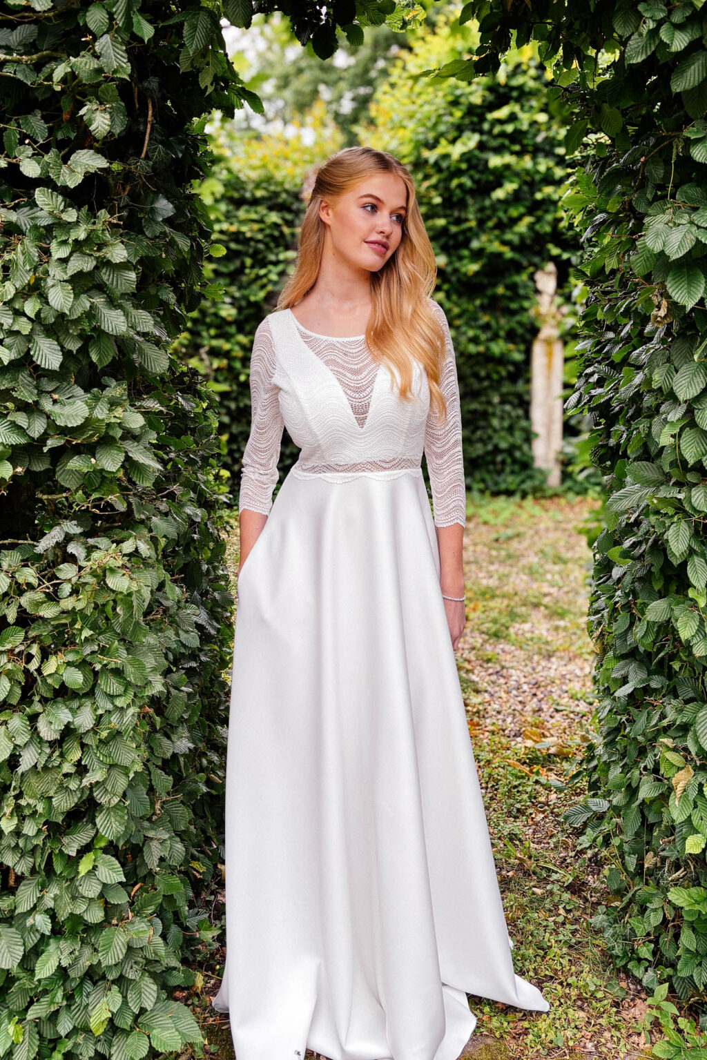 Brautkleid KUESSdieBOBIGNY in A-Linie mit 3/4-Arm aus Wellenspitze unter einem Efeubogen