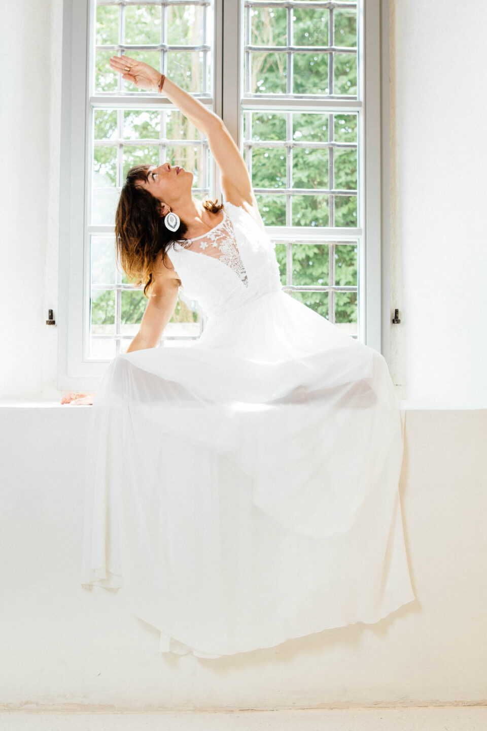 Brautkleid mit 3D-Spitze Bibbona, Braut in Yoga-Pose auf der Fensterbank