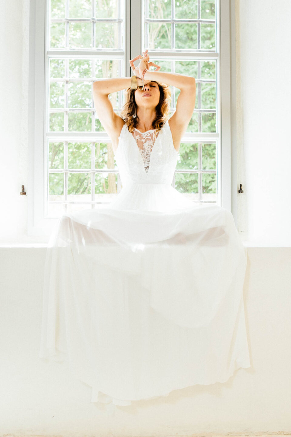 Brautkleid Bibbona mit tiefem V-Ausschnitt und weitem Chiffonrock, Braut auf der Fensterbank