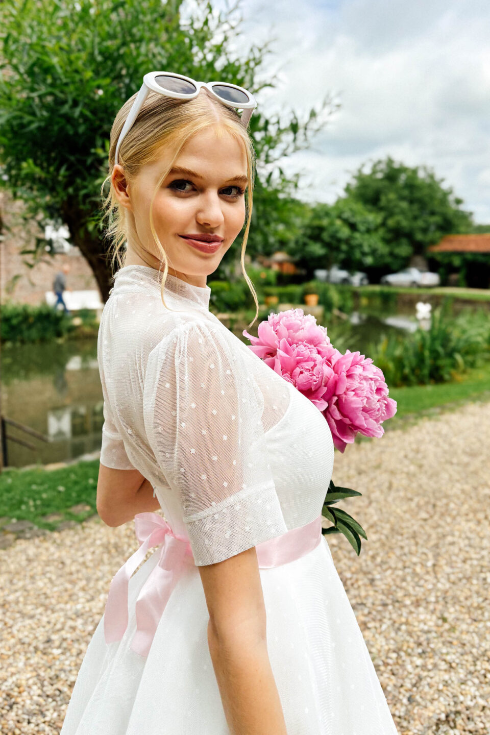 Brautkleid im 50er-Jahre-Stil KUESSdieBARLETTA mit Tupfen-Tüll, Puffärmeln und rosé Satinschleife, Braut mit Pfingstrosen